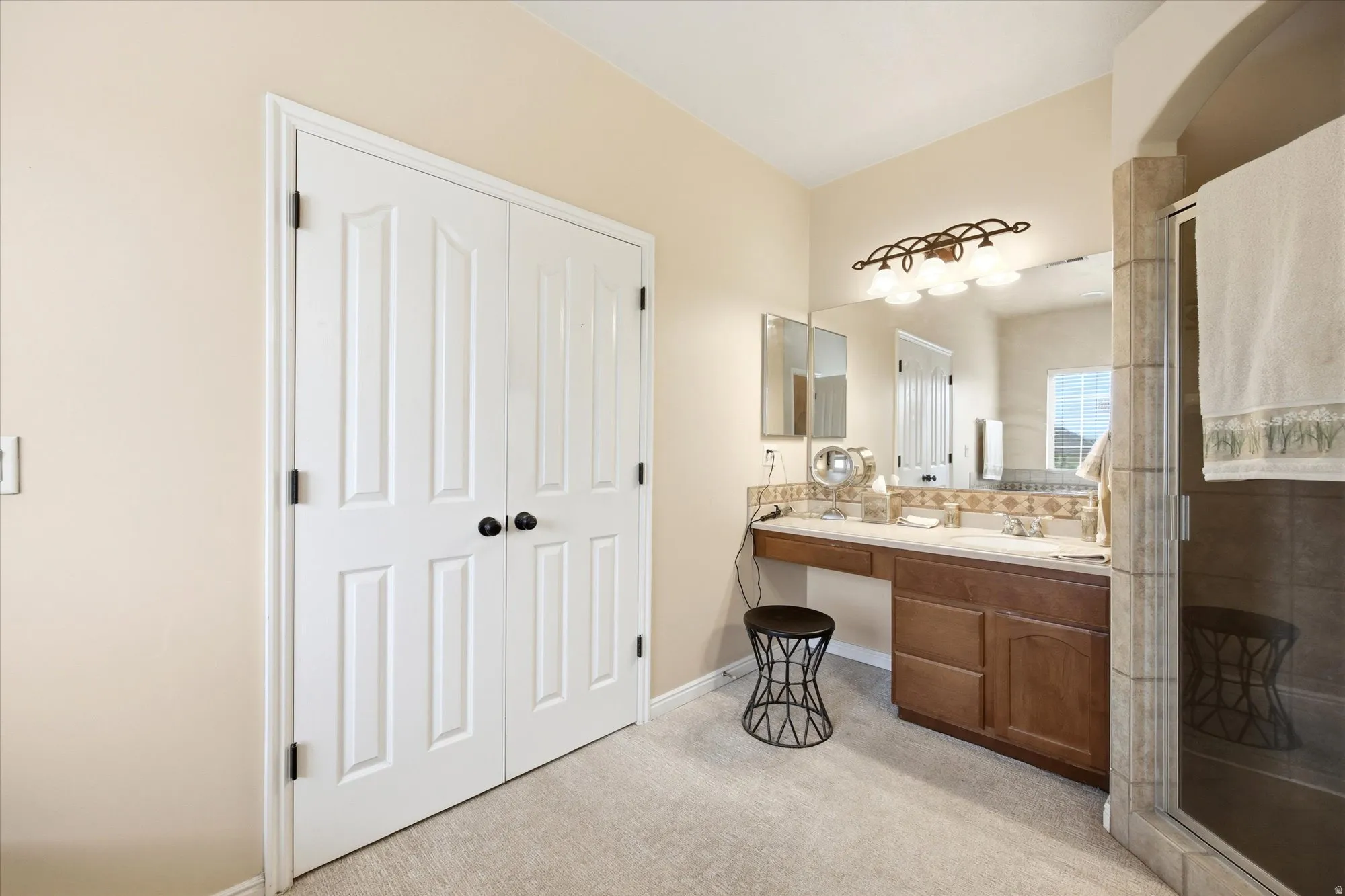 Bathroom featuring a double vanity with built-in cabinetry, dual sinks, and a large wall mirror
