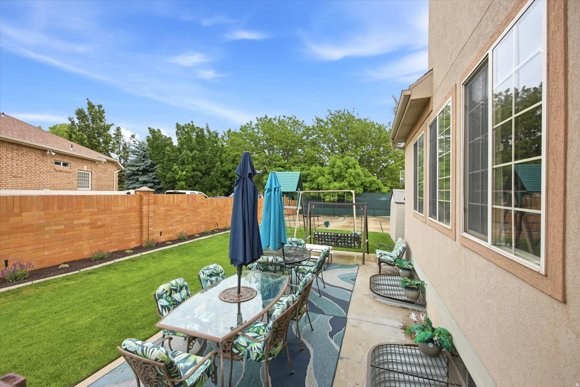 Expansive backyard featuring a manicured lawn, a concrete patio, and a brick privacy wall