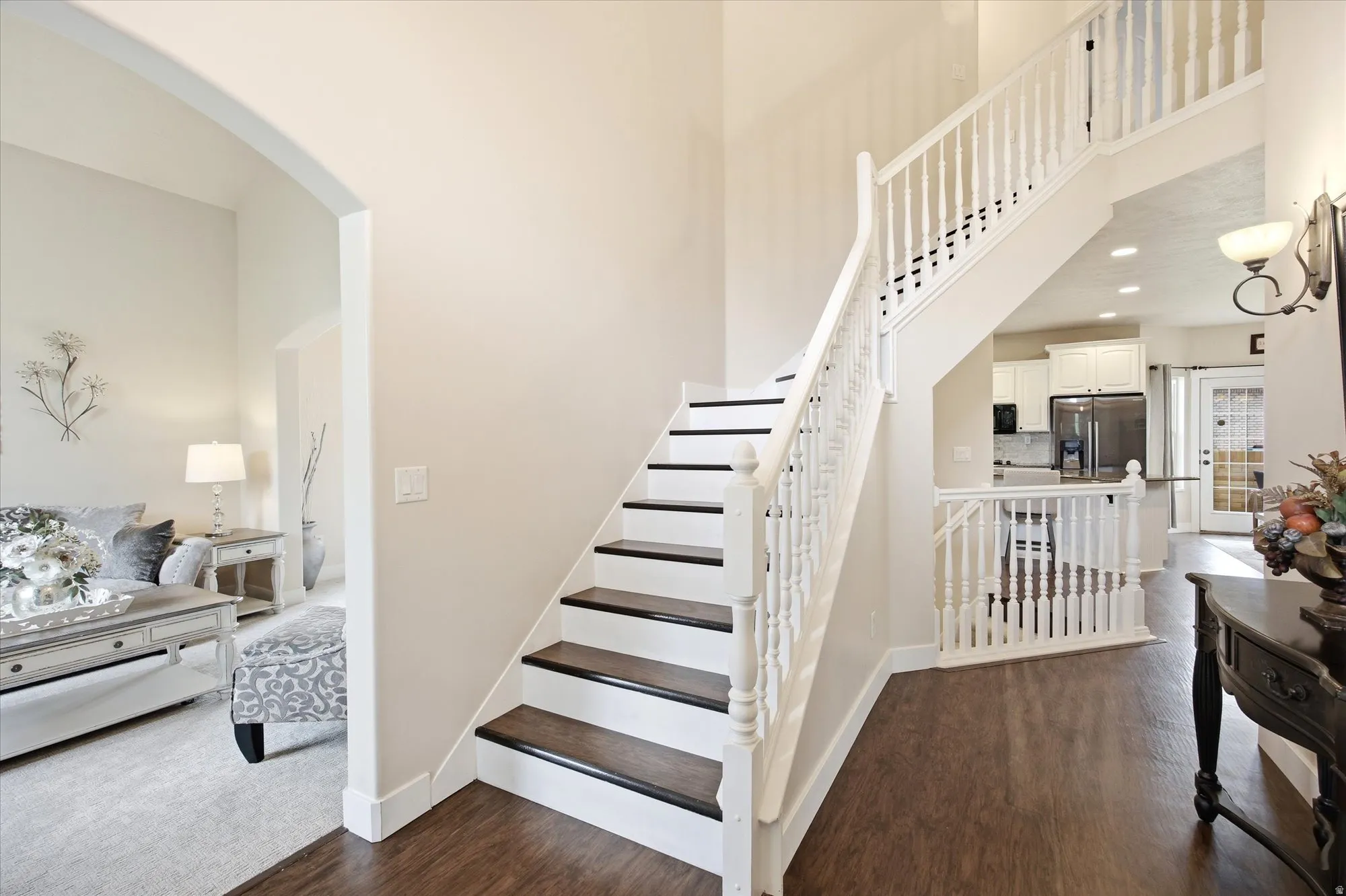 Two-story foyer featuring dark wood-finish flooring and a white spindle staircase