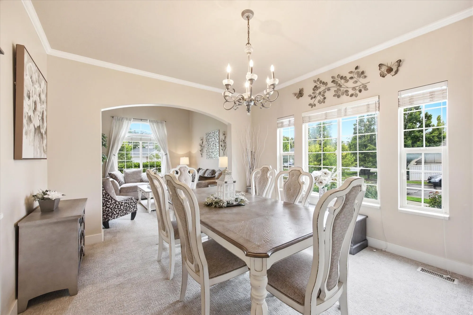 Elegant dining space featuring a chandelier, crown molding, and multiple windows with grid patterns