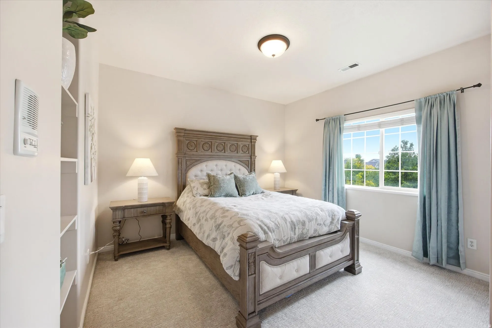 Bright bedroom featuring a large window, soft carpeting, and a ceiling-mounted light fixture