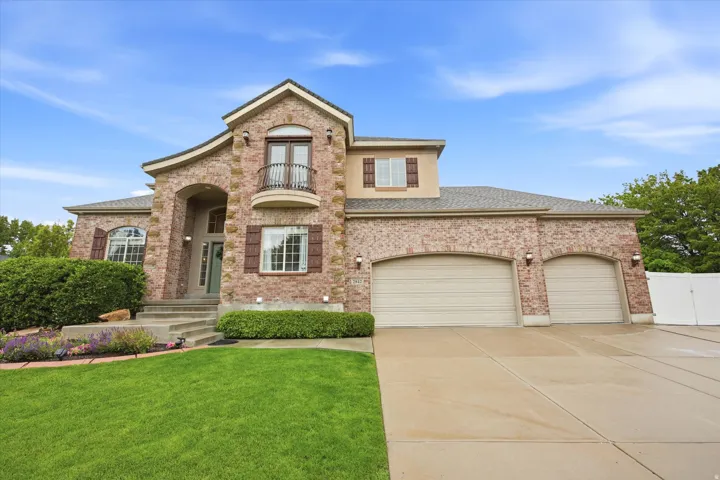 Brick facade residence featuring an arched portico entry, a second-story Juliet balcony, and decorative exterior shutters