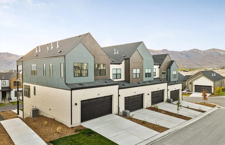 Modern townhome exterior featuring multi-toned siding, black frame windows, and an attached two-car garage