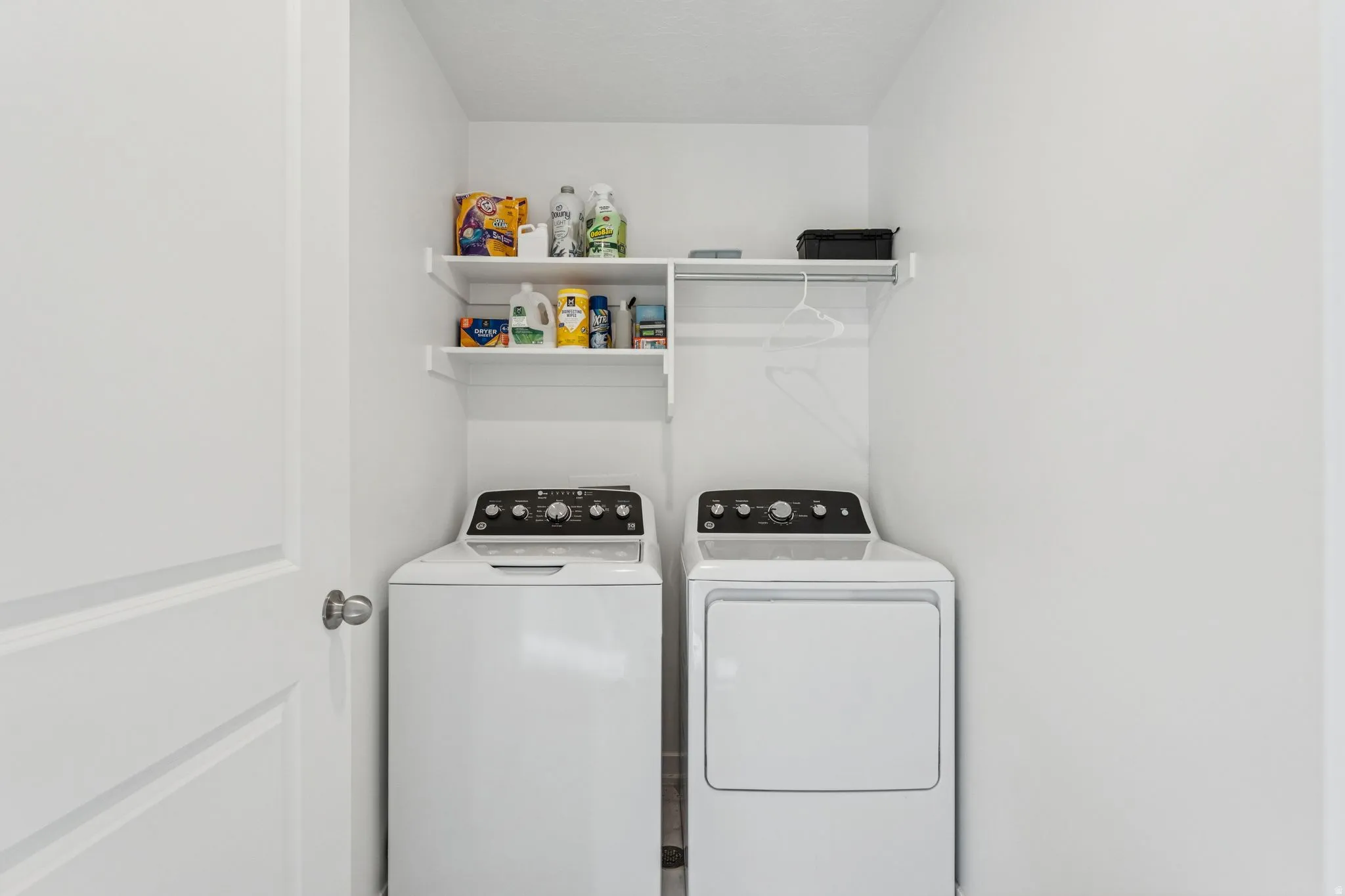 Dedicated laundry alcove with overhead shelving and a clothing rod