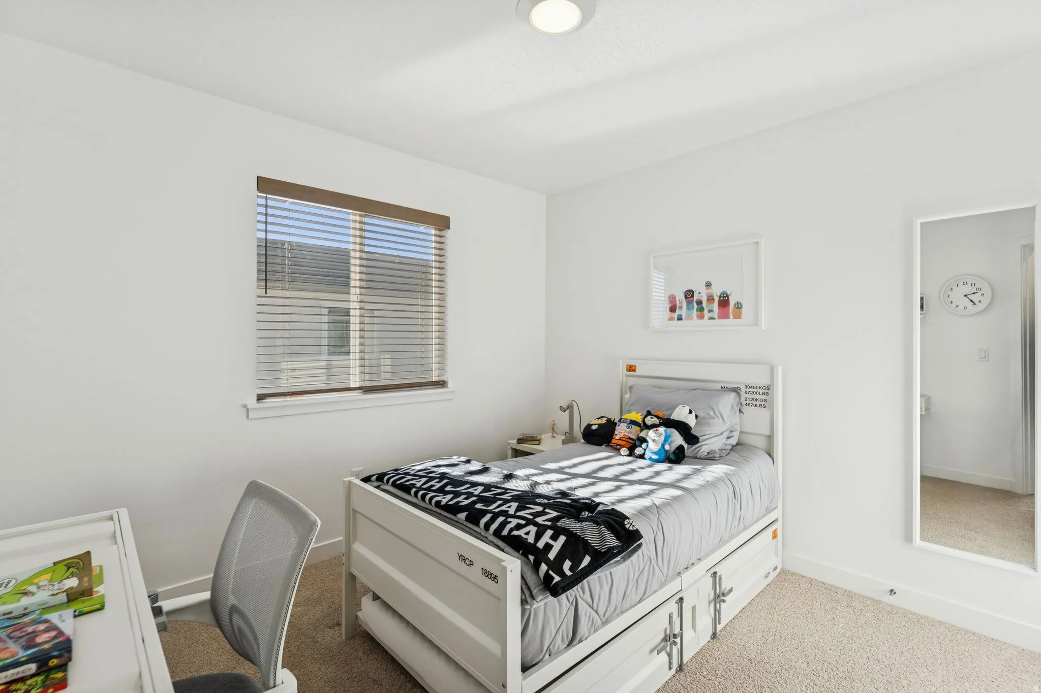 Recessed ceiling lighting illuminates a room featuring white walls, a single window with blinds, and carpeted flooring