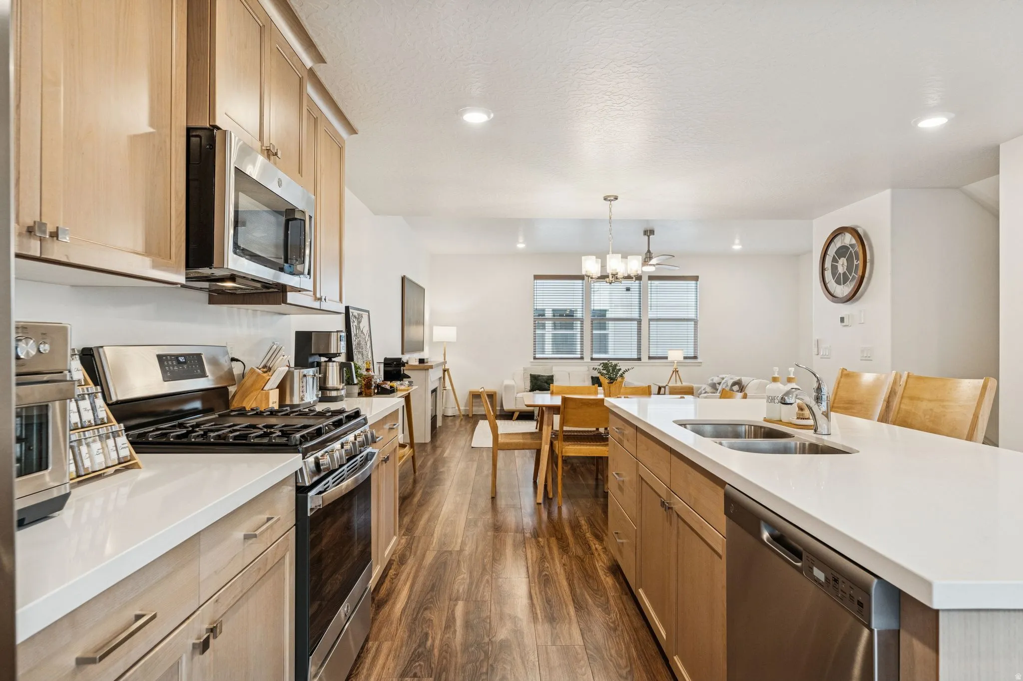 Kitchen featuring stainless steel appliances, light wood-finish cabinetry, white countertops, a double-basin sink, and wood-finish flooring