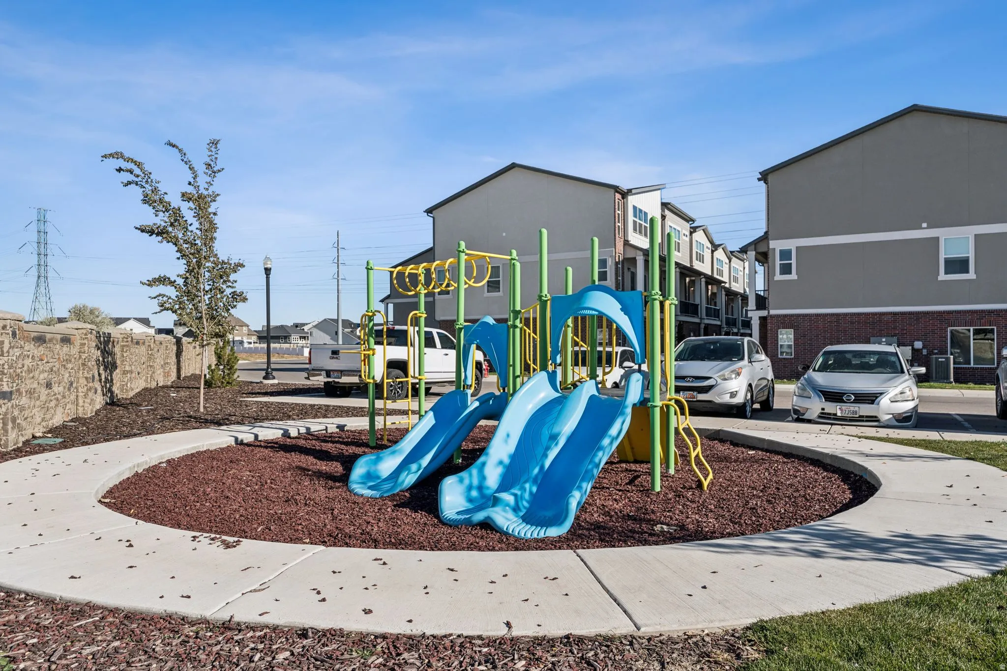 Community playground featuring multiple slides, climbing elements, and a surrounding concrete path