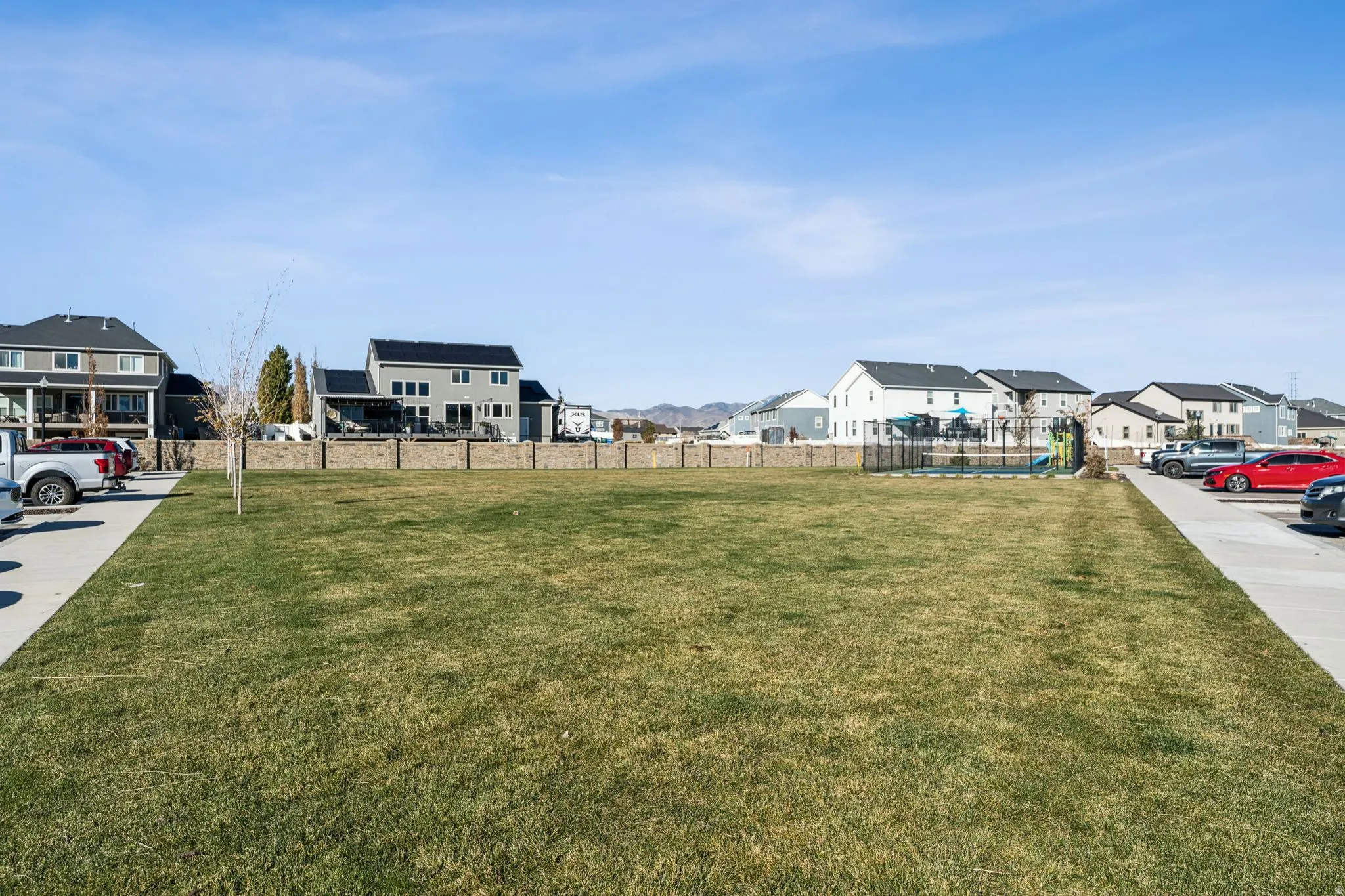 Expansive green space featuring a manicured lawn and a perimeter brick wall