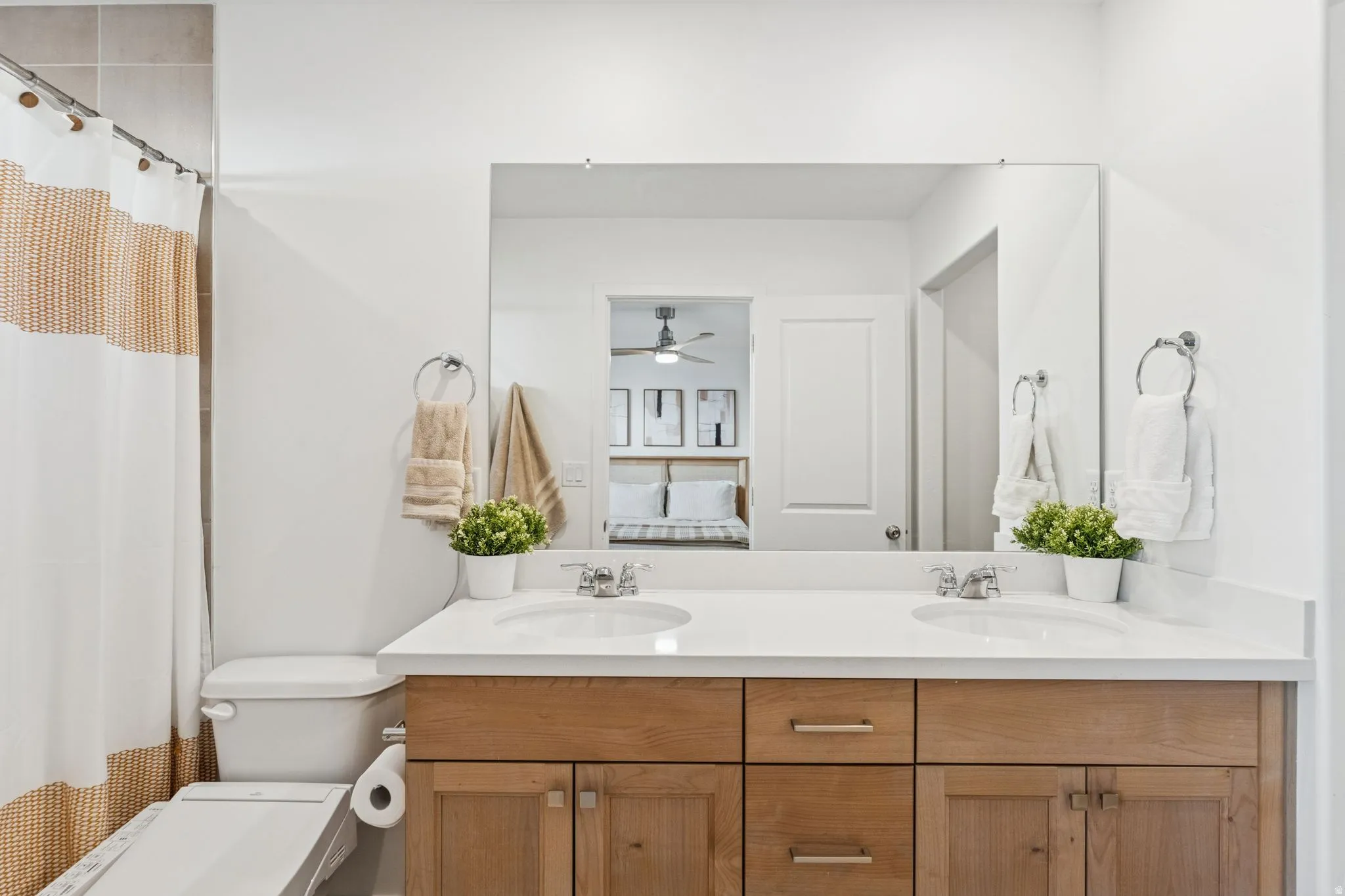 Dual vanity with wood cabinetry, white countertops, and chrome fixtures