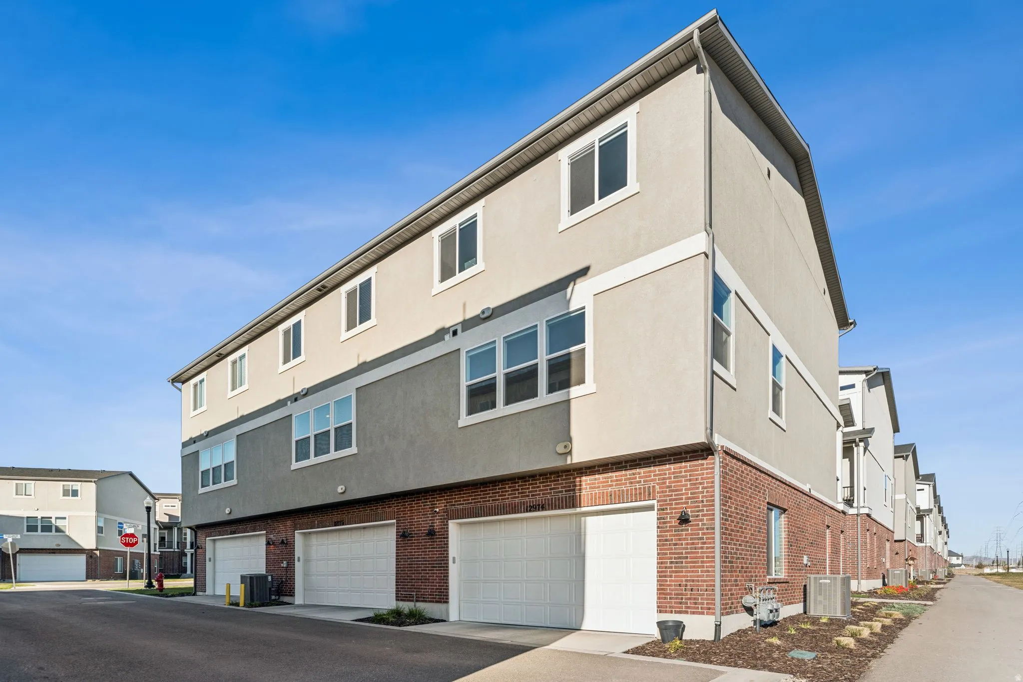 Contemporary townhome exterior featuring a brick facade on the lower level and stucco on the upper levels