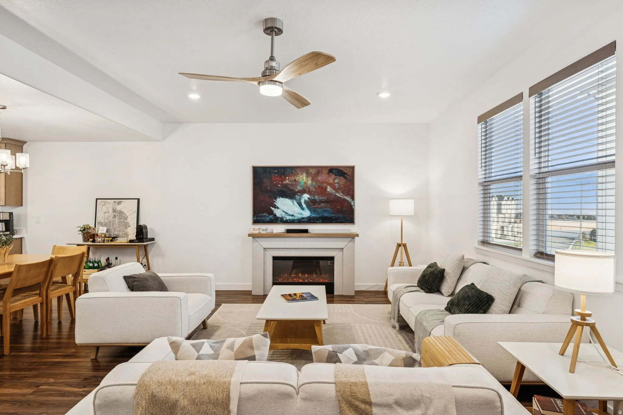 Open concept living area featuring wood-finish flooring, a ceiling fan with integrated lighting, recessed lighting, and large windows with blinds