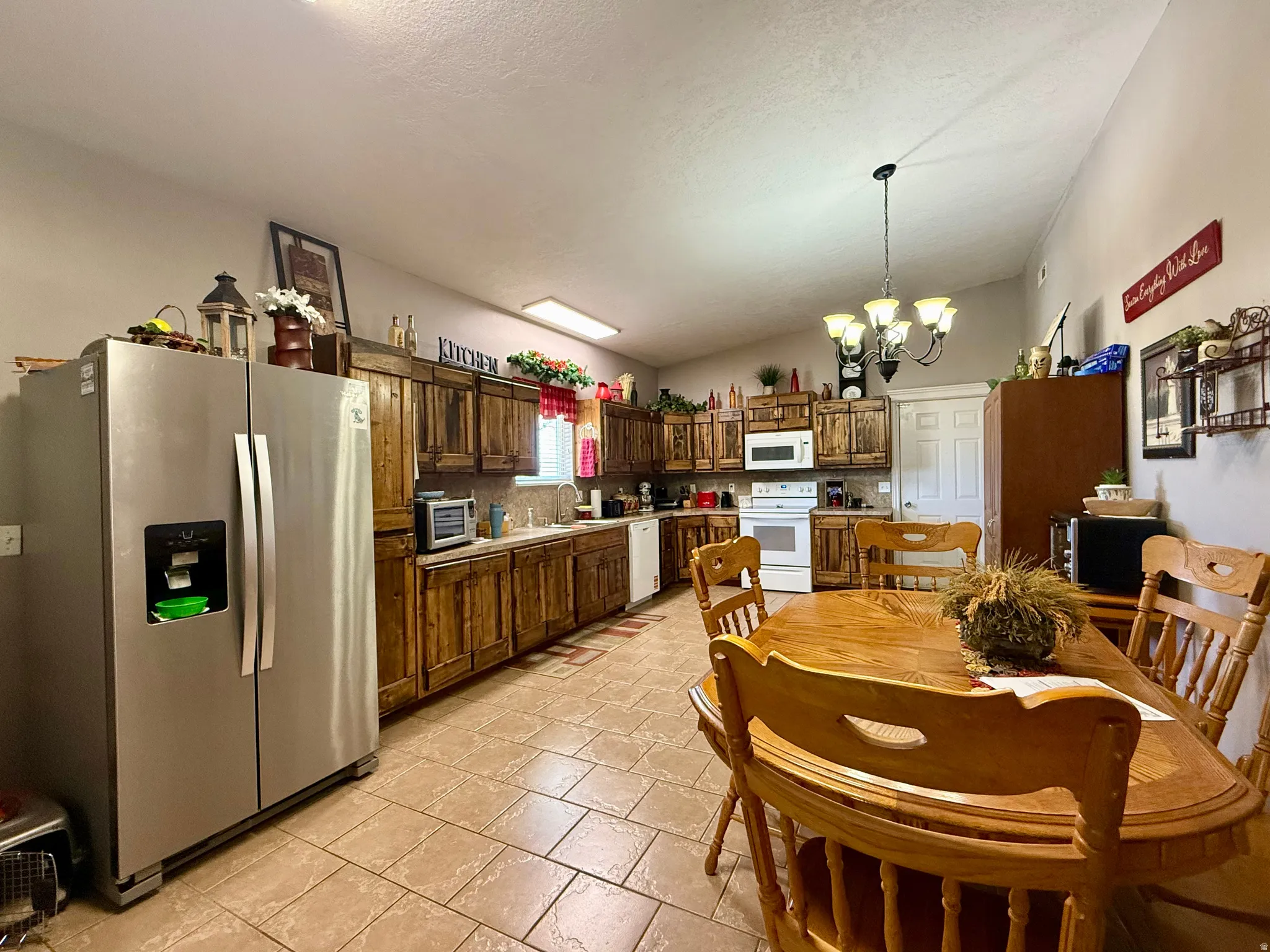 Spacious kitchen featuring wood cabinetry, stainless steel refrigerator, white oven, white microwave, and tile flooring
