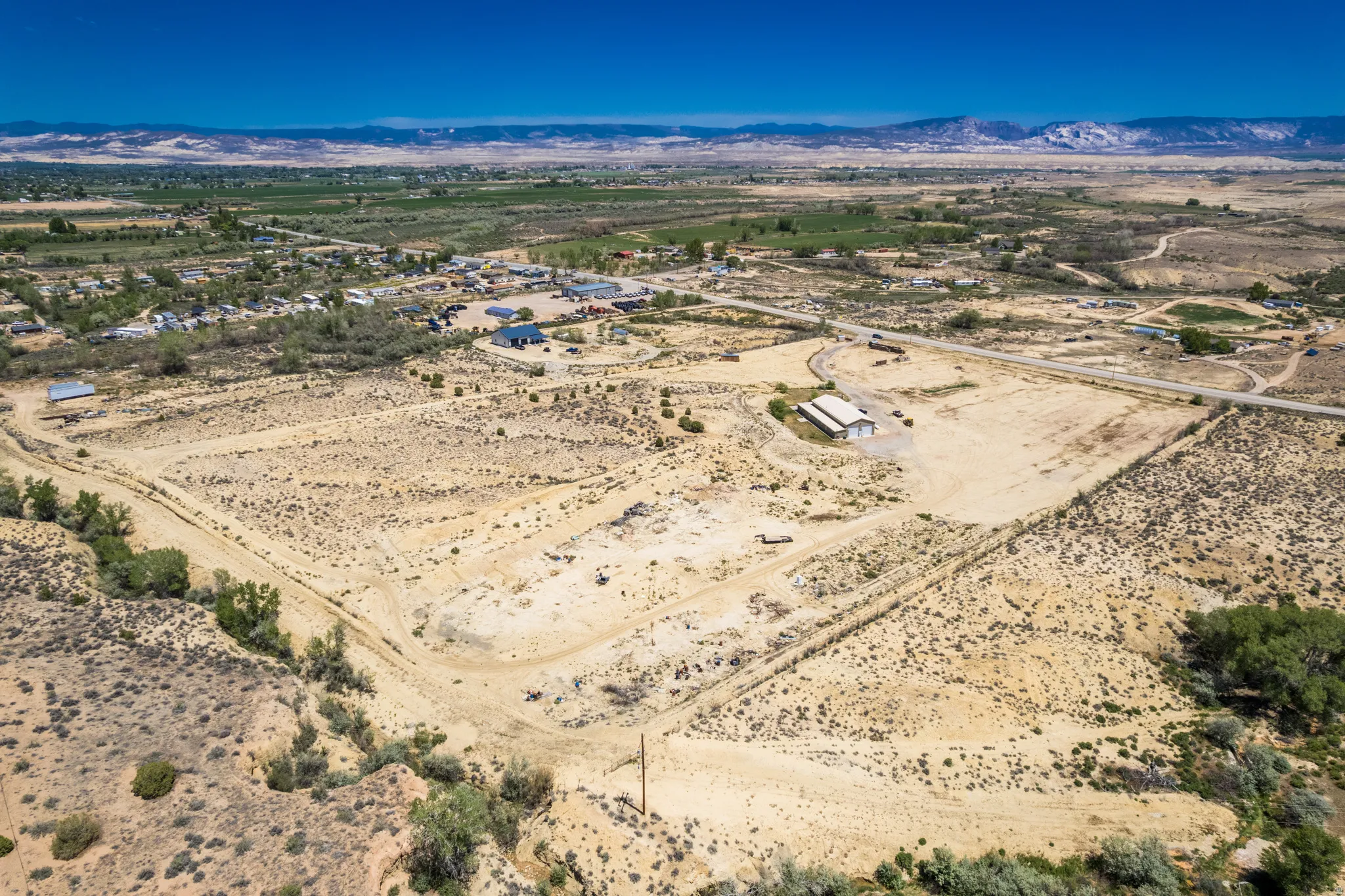 Expansive undeveloped land with a single-story structure and a paved road frontage