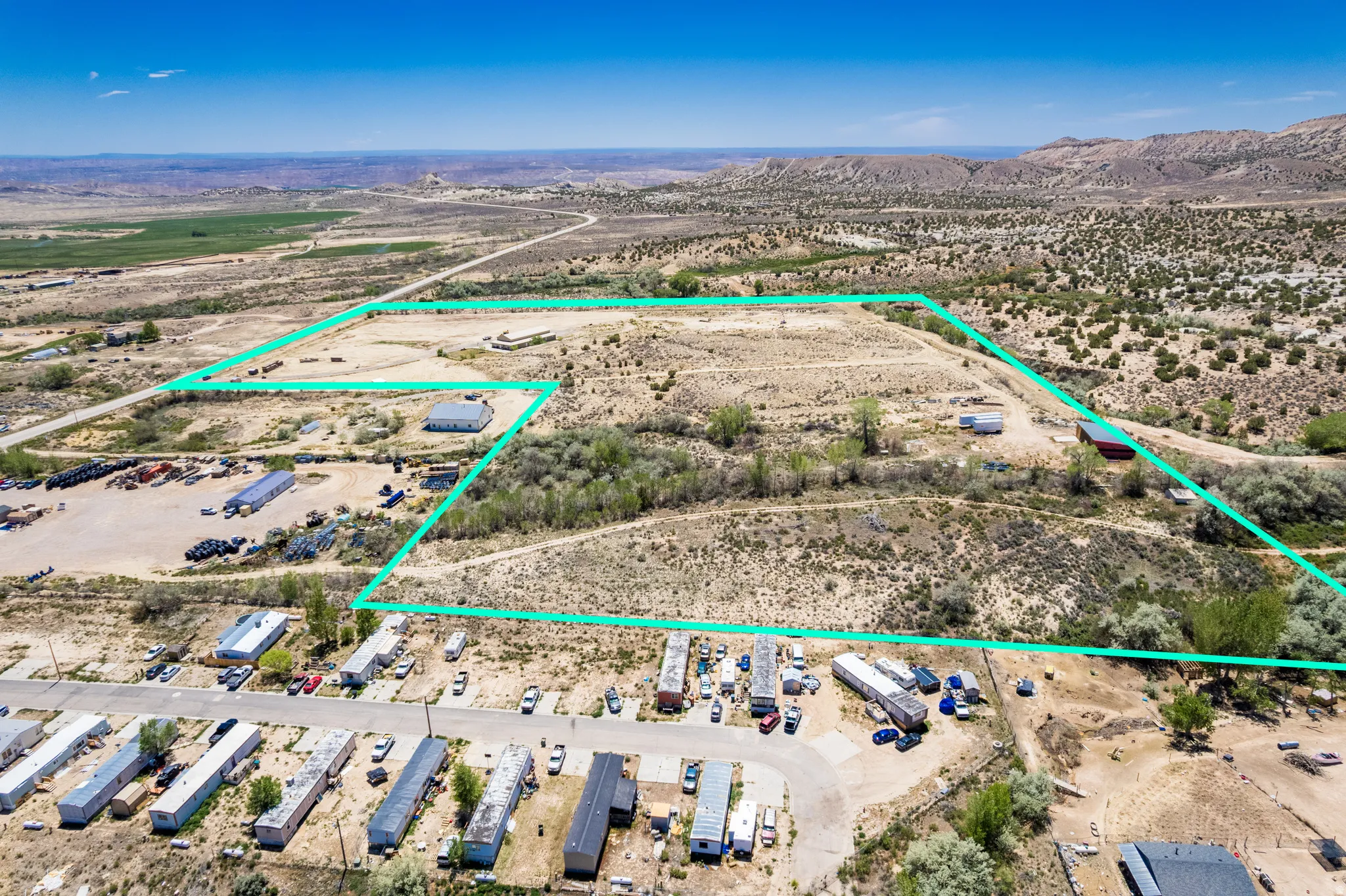 Expansive desert acreage featuring a clear blue sky, distant hills, and varied topography