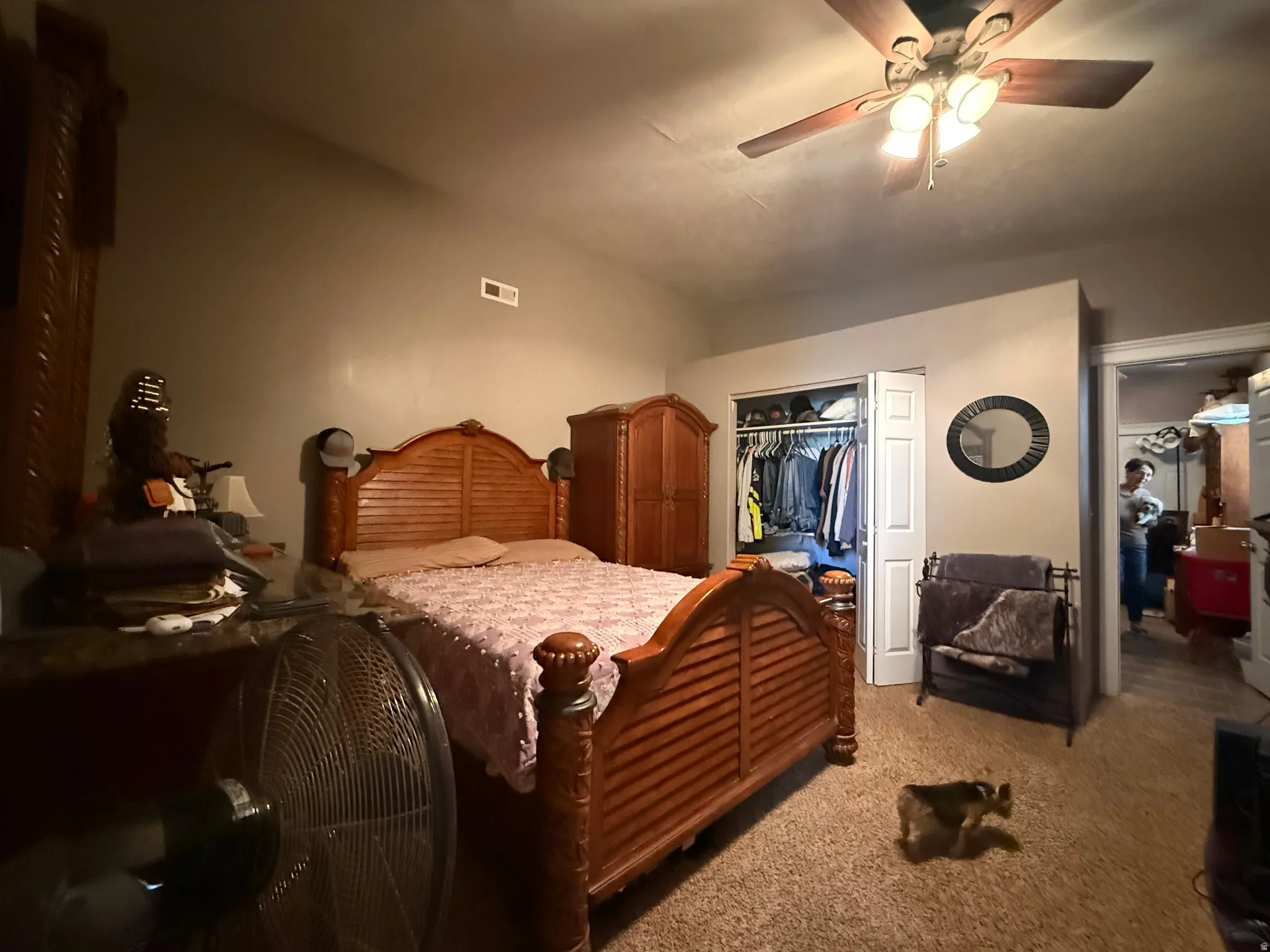 Carpeted room featuring a ceiling fan with integrated lighting, a built-in closet with double bifold doors, and a doorway leading to an additional interior space