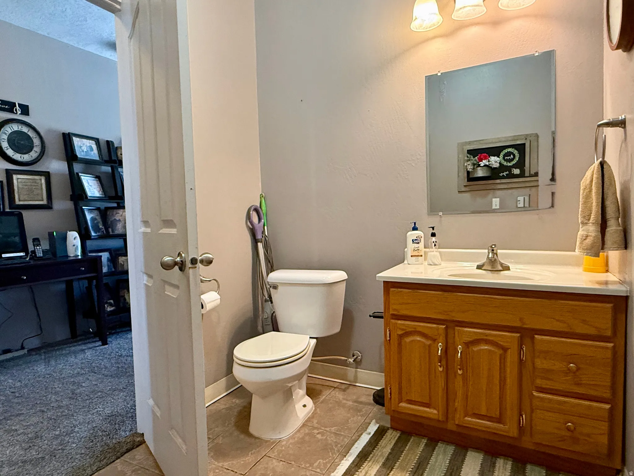 Bathroom featuring a wood-finish vanity with a single basin sink and a light-colored countertop