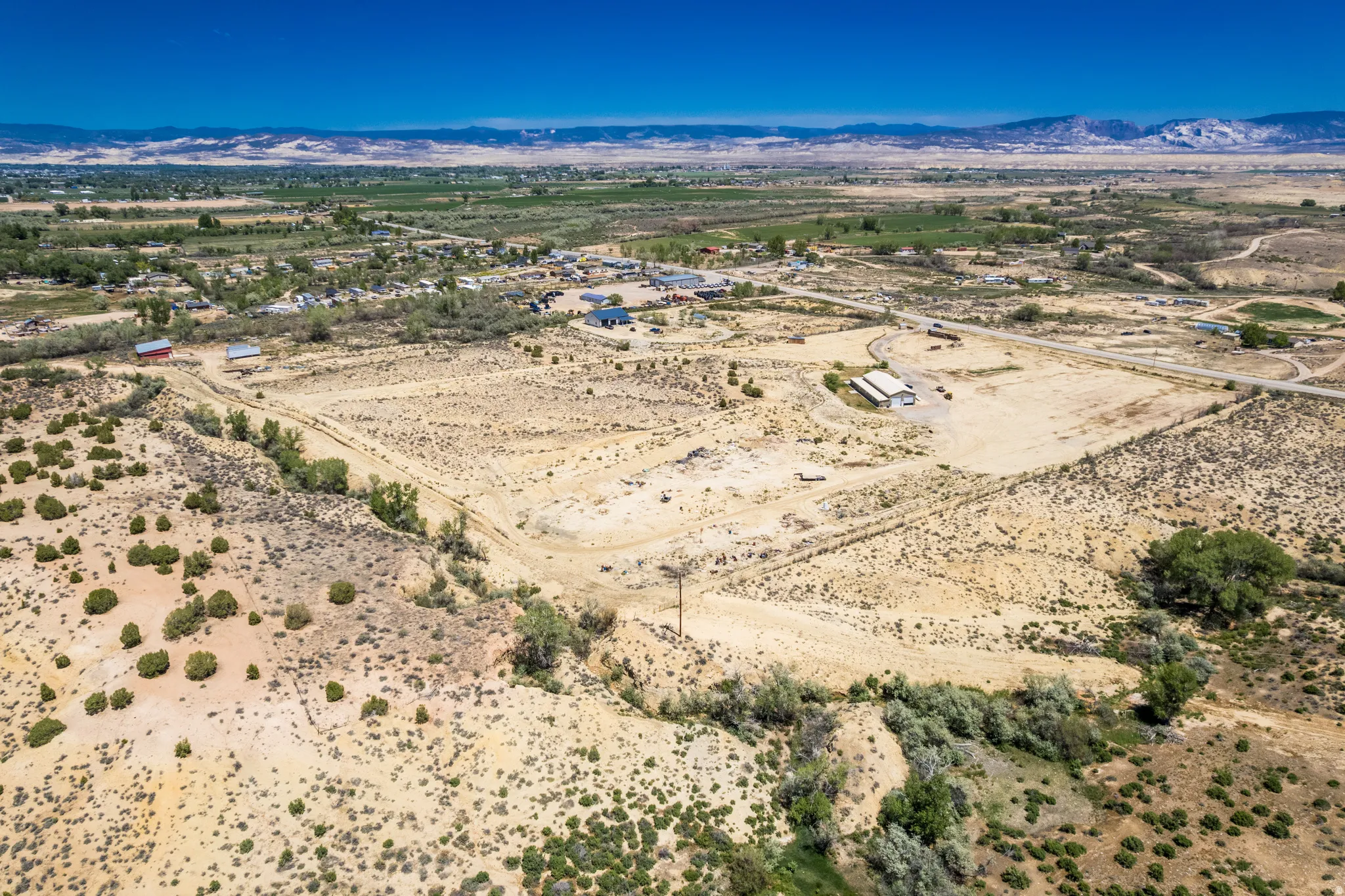 Expansive arid landscape featuring scattered green vegetation and distant mountain ranges