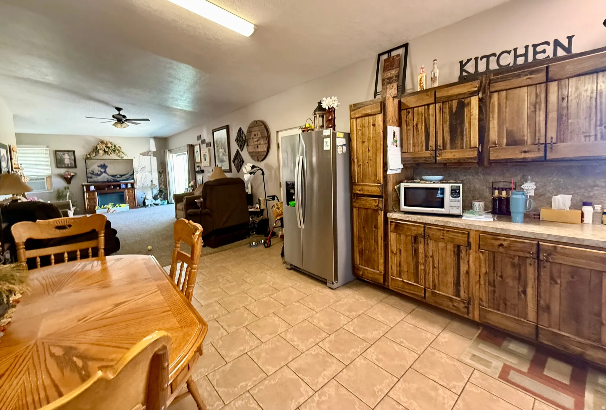 Galley kitchen featuring wood-finish cabinetry, light-toned countertops, and a full-size stainless steel refrigerator