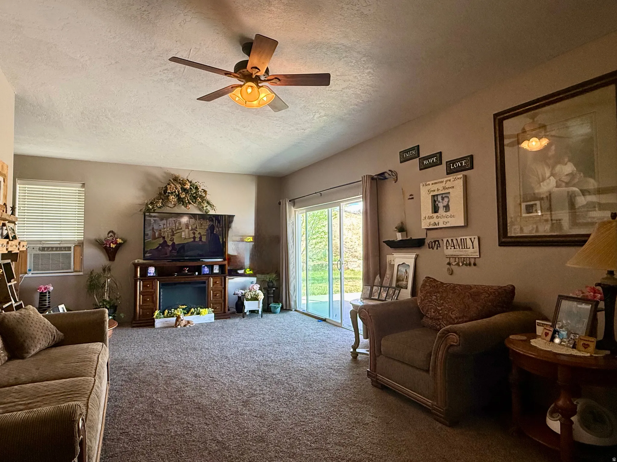Spacious living area featuring neutral carpeting and a ceiling fan