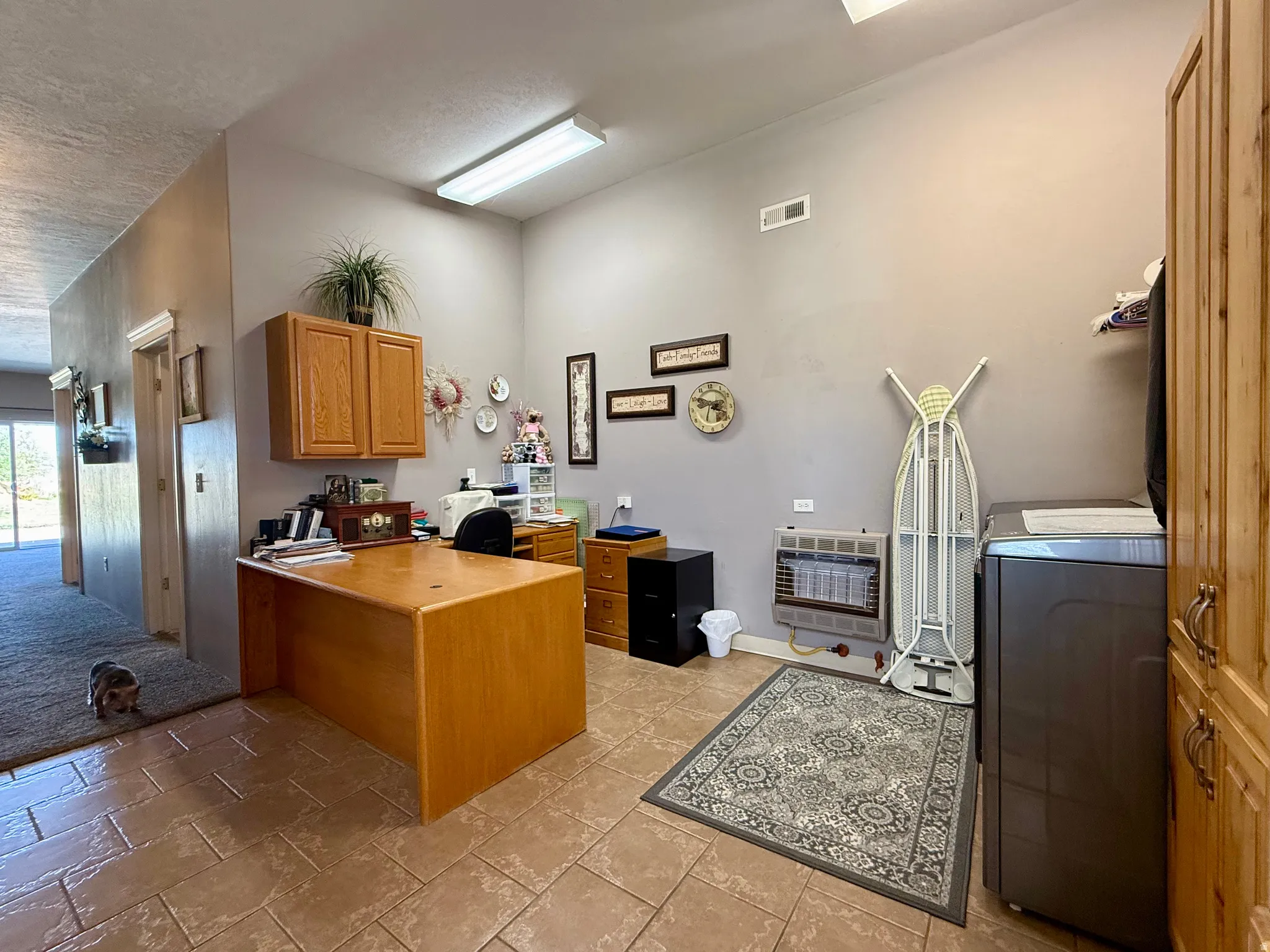 Versatile room featuring tile flooring, neutral wall paint, and a built-in wall cabinet with wood-finish doors