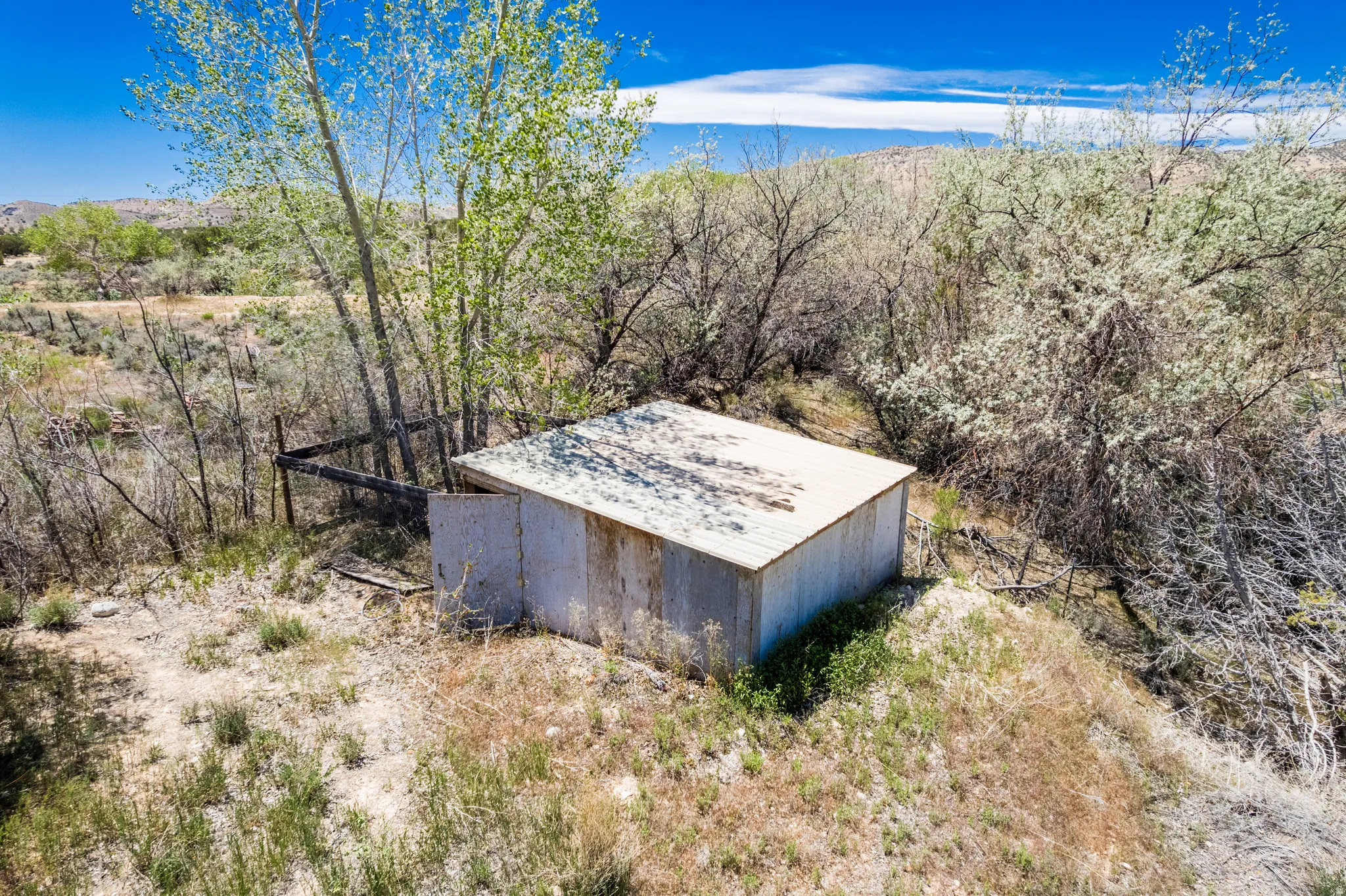 Small utility structure with a corrugated metal roof and wood siding