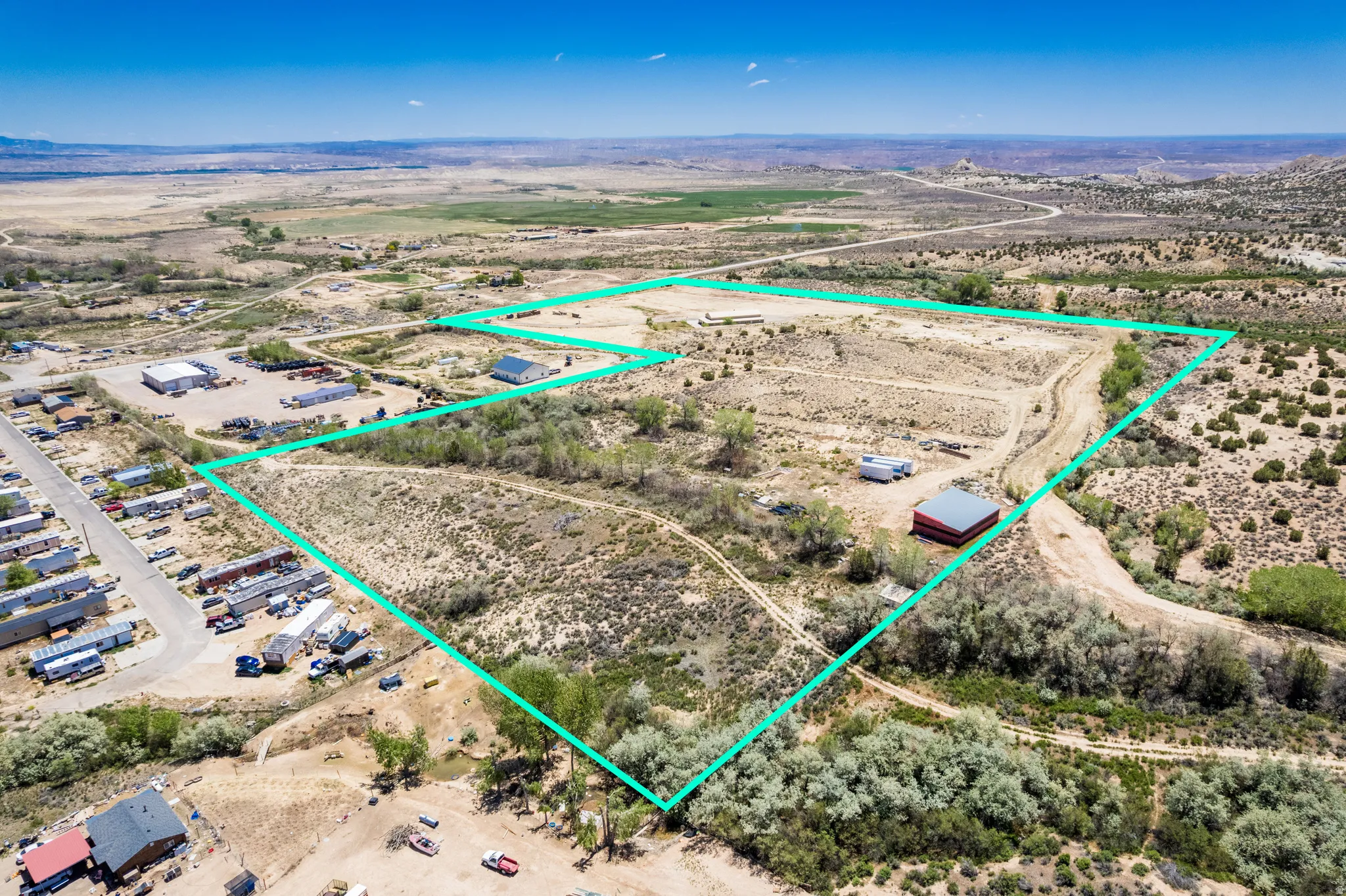 Expansive undeveloped land featuring a red-roofed building, clear perimeter outlining, and natural vegetation