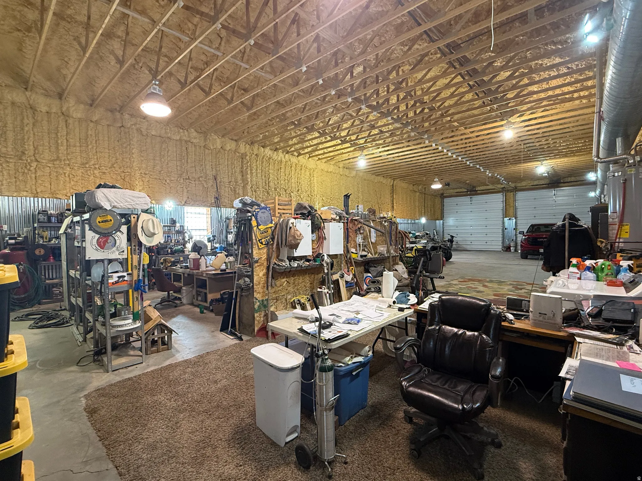 Spacious industrial-style interior with exposed ceiling trusses and spray foam insulation