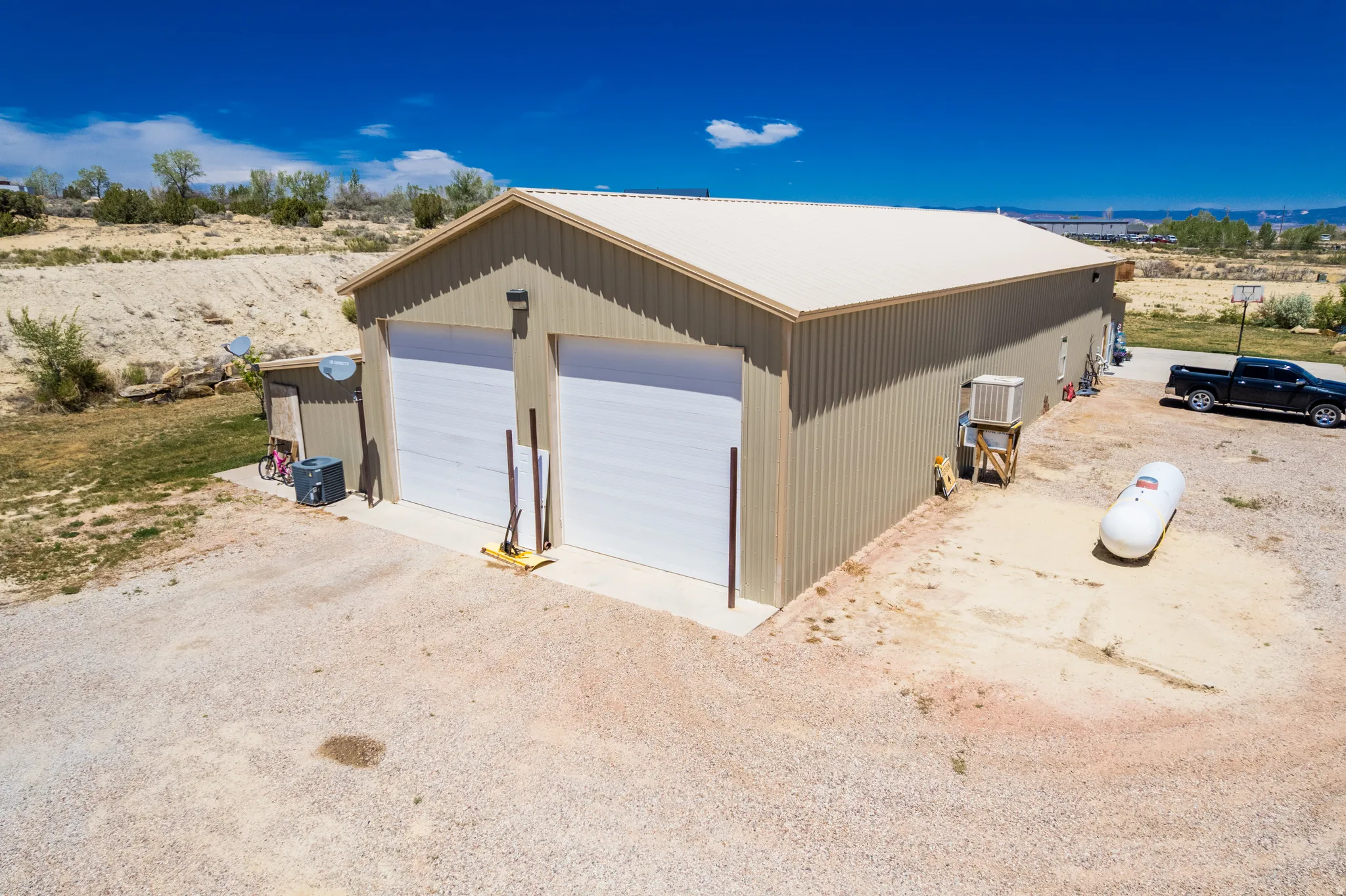 Expansive detached metal structure featuring two garage doors, a light-colored metal roof, and a gravel driveway