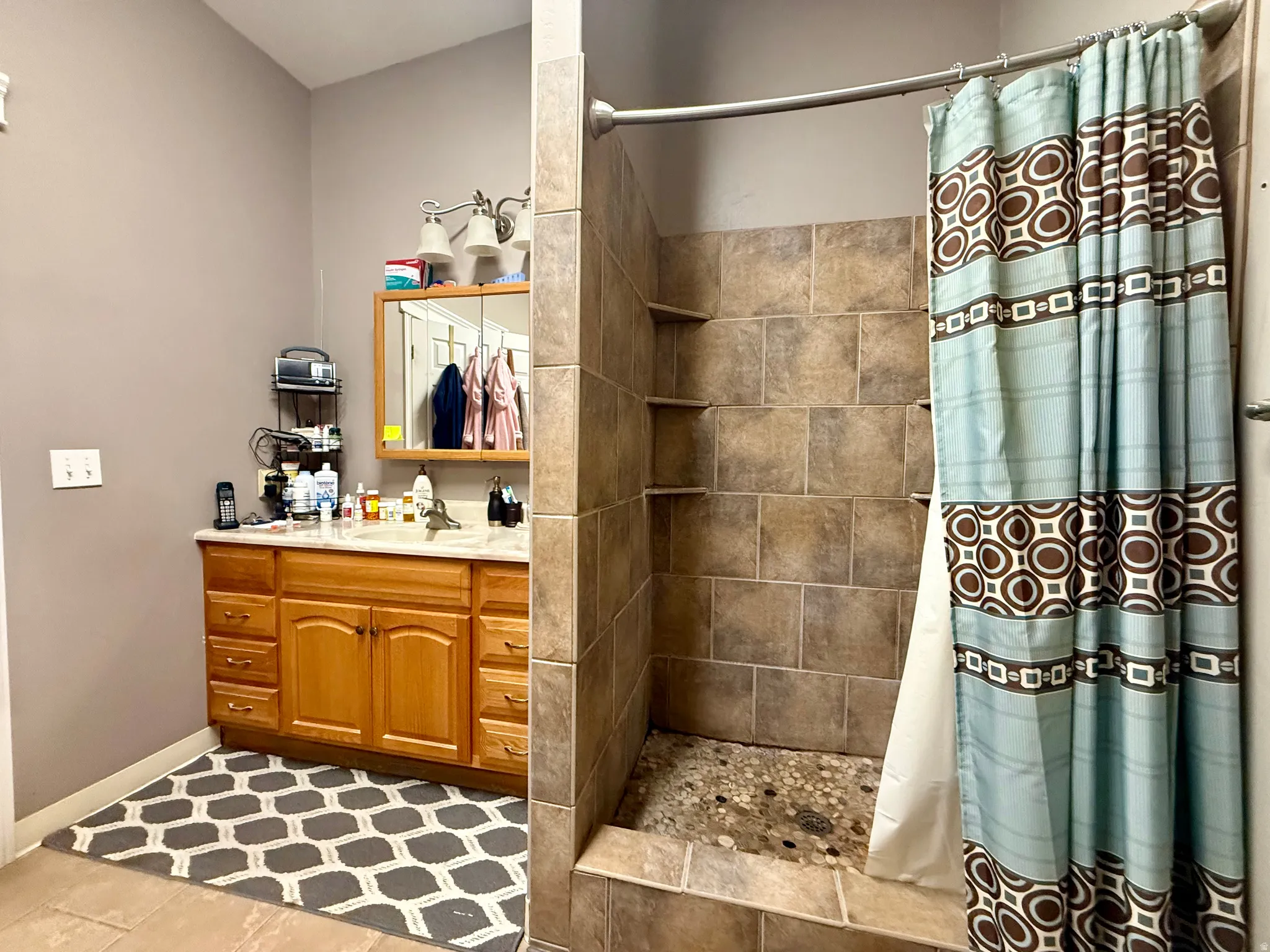 Tiled shower enclosure featuring integrated shelving and a river rock floor
