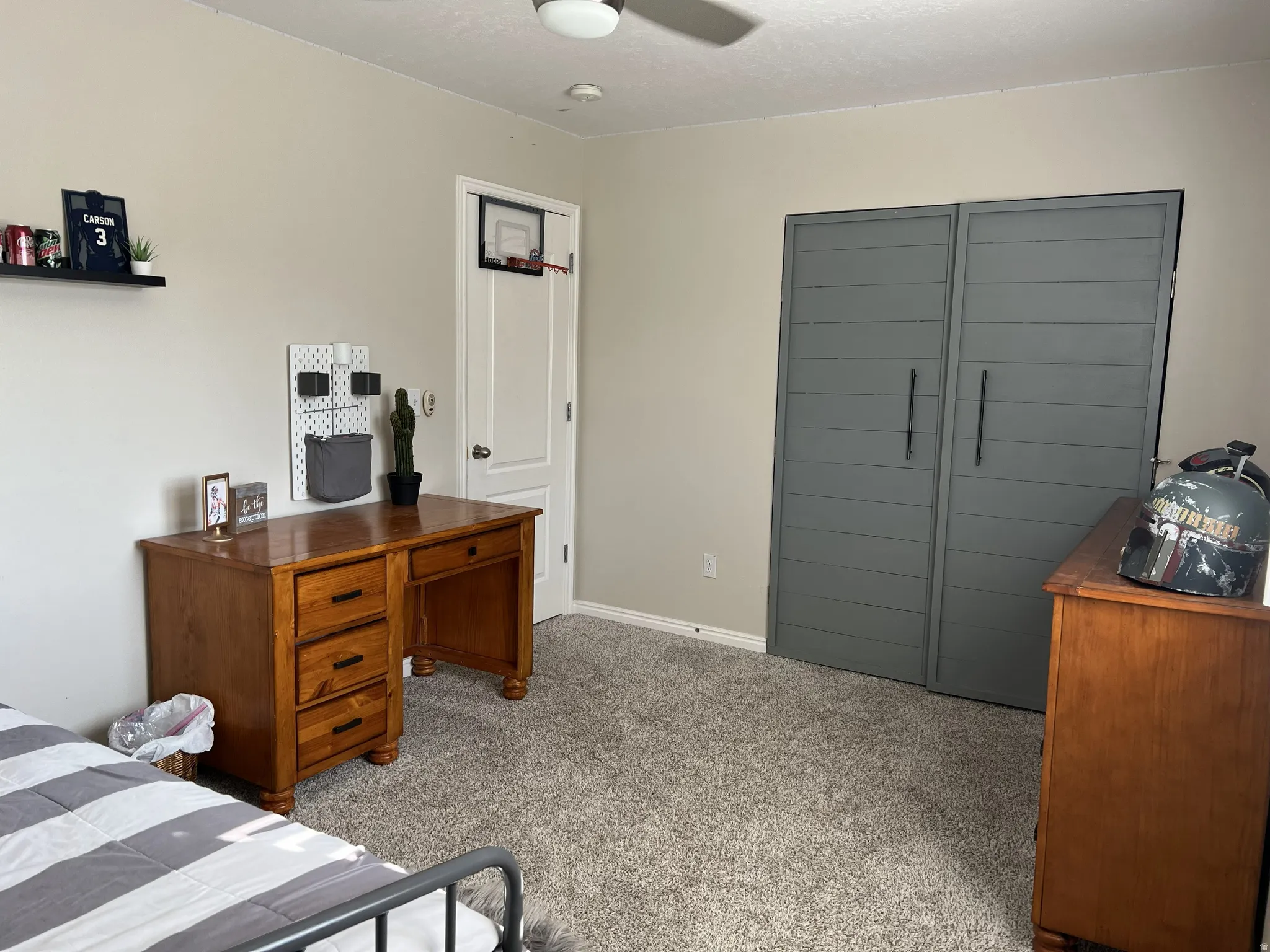 Carpeted room featuring a ceiling fan, a white paneled door, and a built-in closet with shiplap-style doors and dark hardware