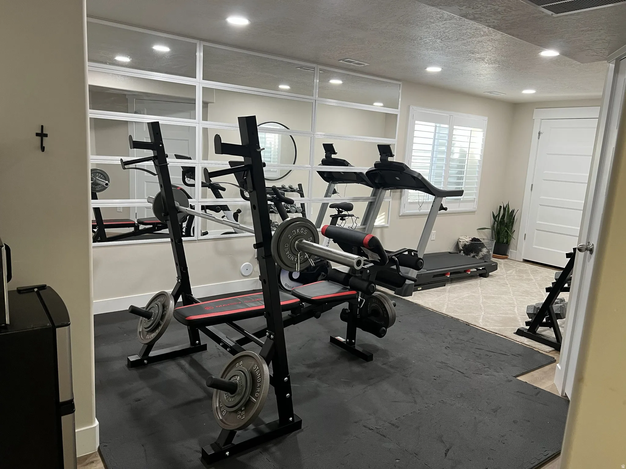Dedicated fitness space featuring mirrored walls and recessed lighting