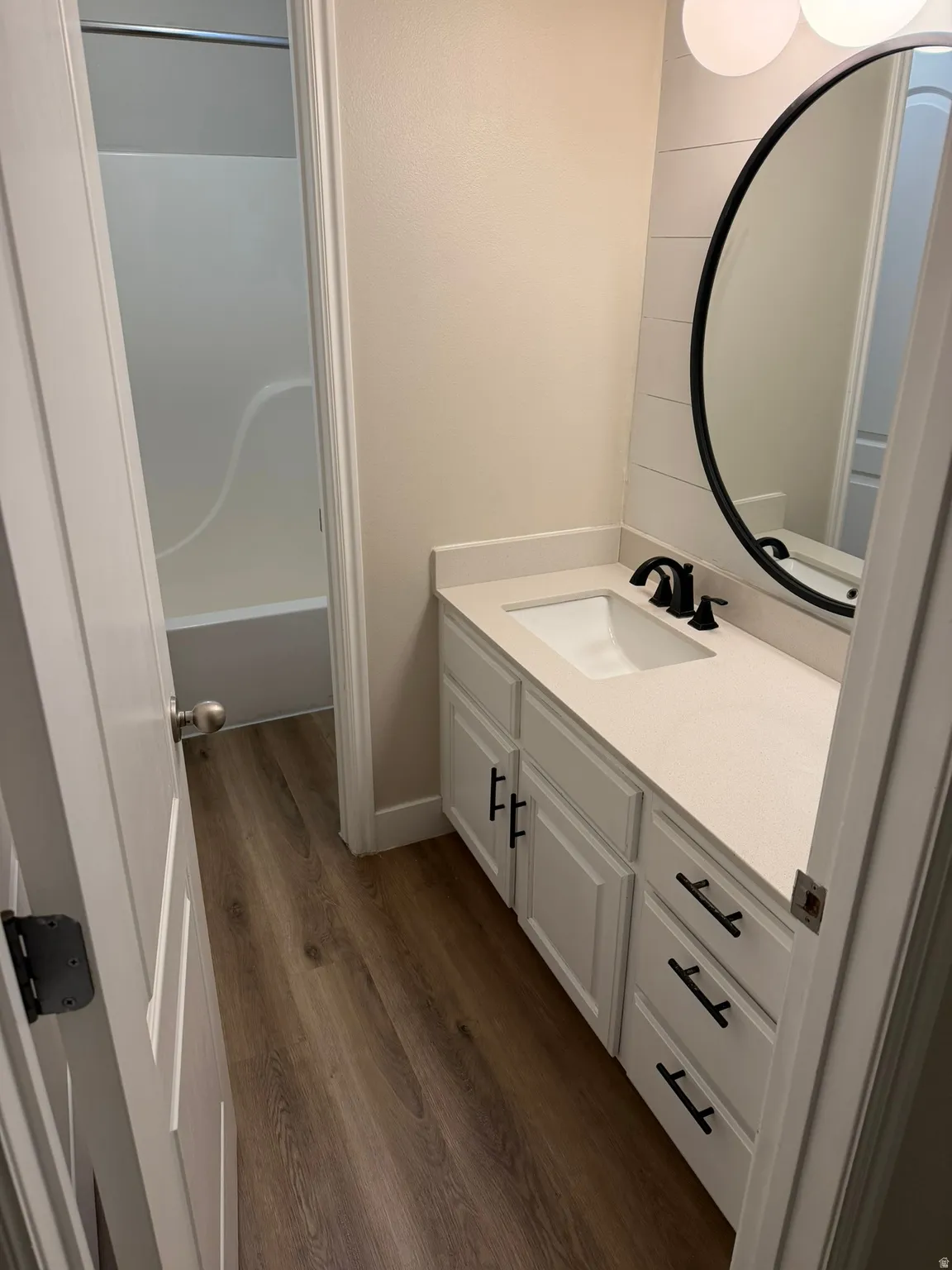 Bathroom featuring a white vanity with paneling and matte black hardware, an integrated rectangular sink, and a light-toned countertop