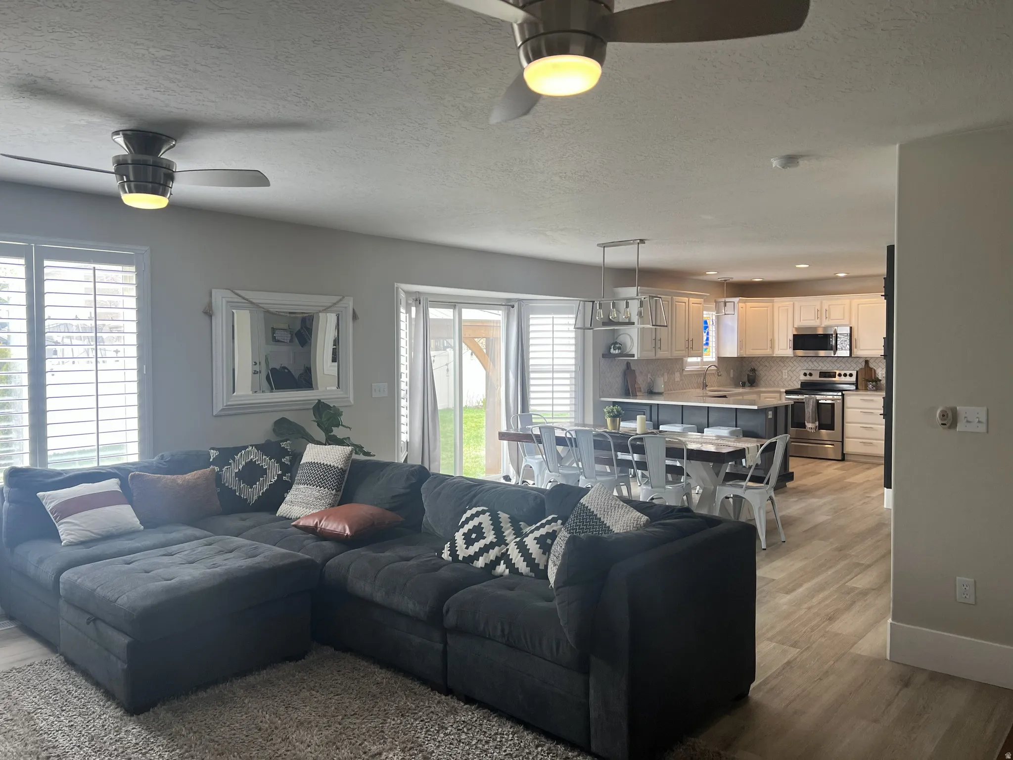 Open-concept living area featuring wood-finish flooring, plantation shutters, recessed lighting, and ceiling fans