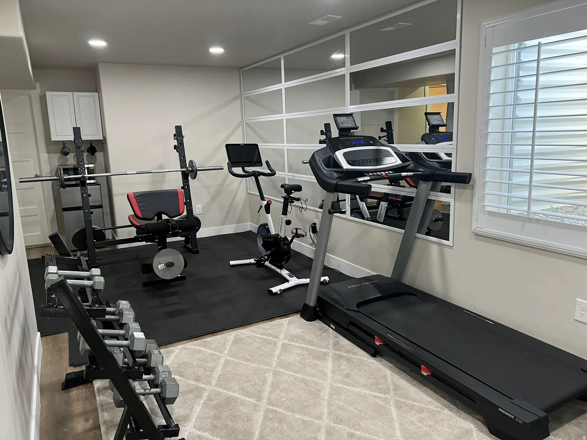 Dedicated exercise space featuring a rubber flooring mat, recessed lighting, and wall-mounted cabinetry