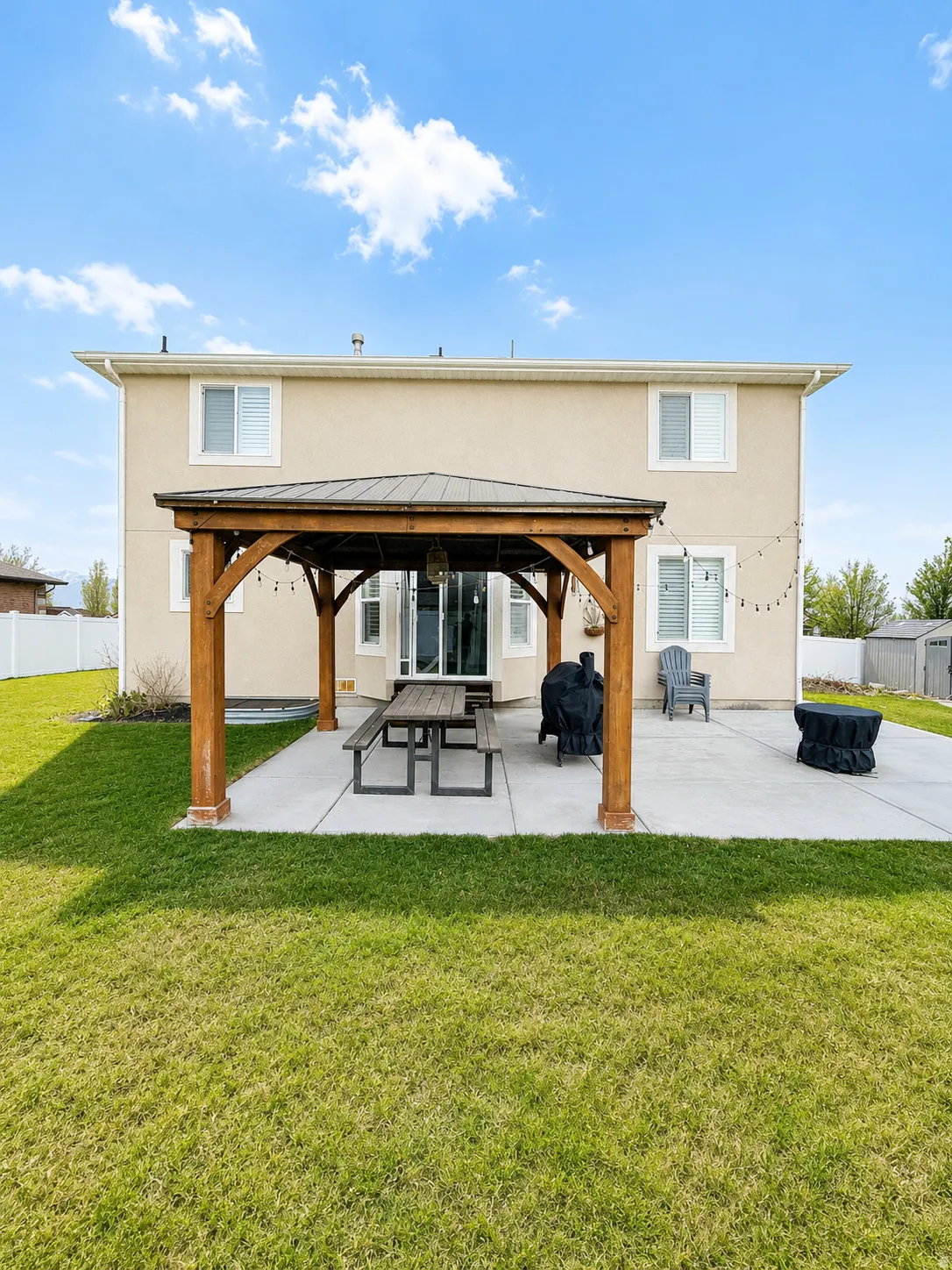 Expansive backyard featuring a concrete patio with a wood-frame gazebo