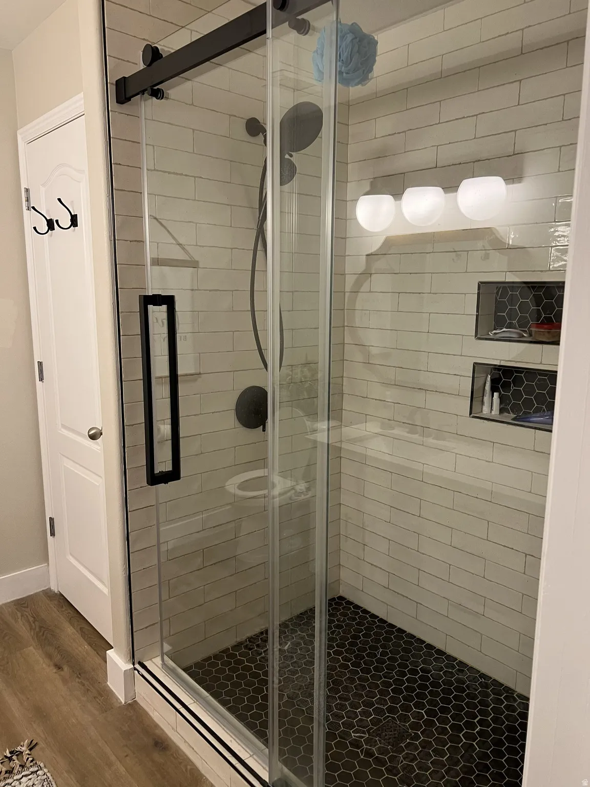 Walk-in shower with clear glass sliding door and matte black hardware