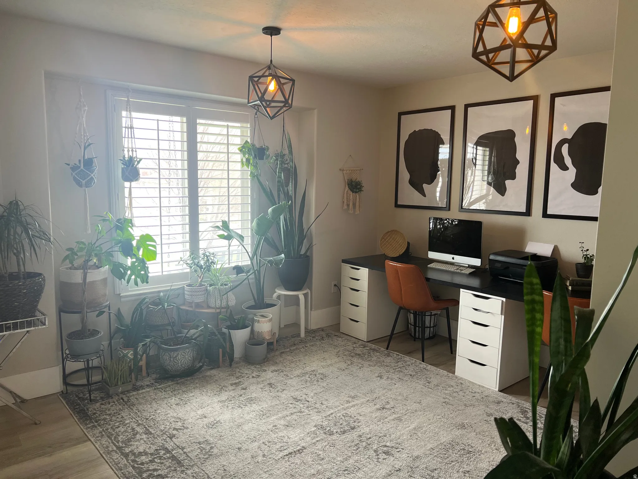 Room featuring wood-finish flooring, a large window with white louvered shutters, and two geometric pendant light fixtures