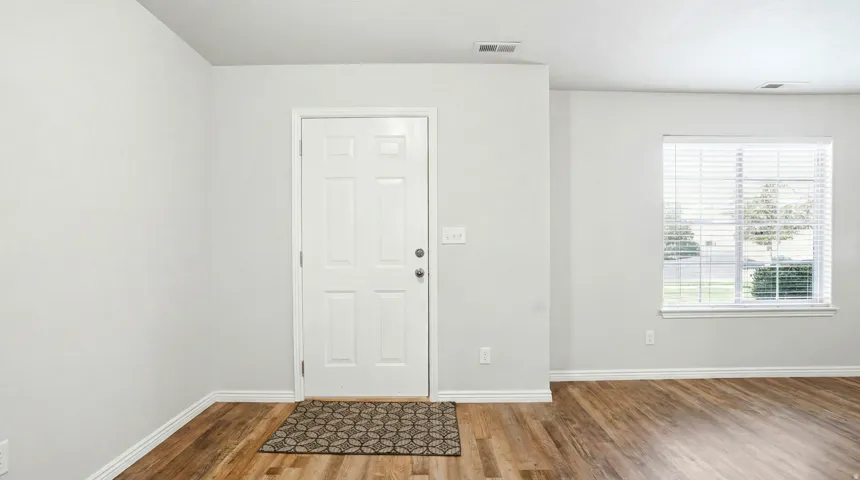 Entryway featuring a white paneled door, wood-finish flooring, and white baseboards