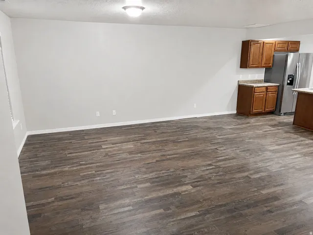 Spacious living area featuring wood-finish flooring, light grey walls, and white trim