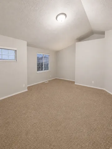 Spacious room featuring neutral carpeting, light-toned walls, and a ceiling-mounted light fixture
