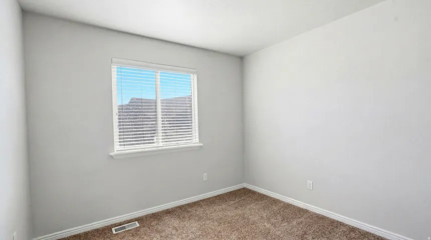 Neutral-toned room featuring a window with horizontal blinds and white trim
