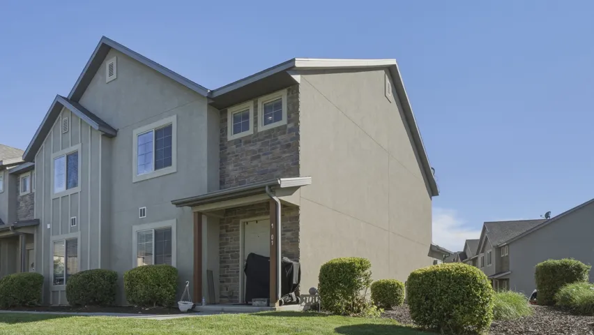 Multi-story residential exterior featuring stucco siding and stone veneer accents