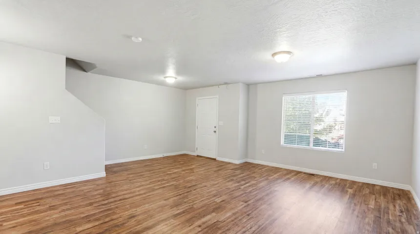 Spacious room featuring wood-finish flooring, white baseboards, and light gray walls