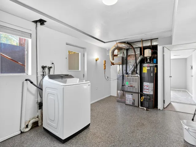 Dedicated laundry area featuring a utility sink connection, window for natural light, and durable speckled flooring