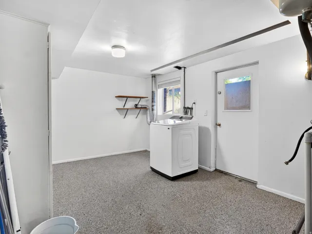 Utility area featuring durable speckled flooring, bright white walls, and a window for natural light