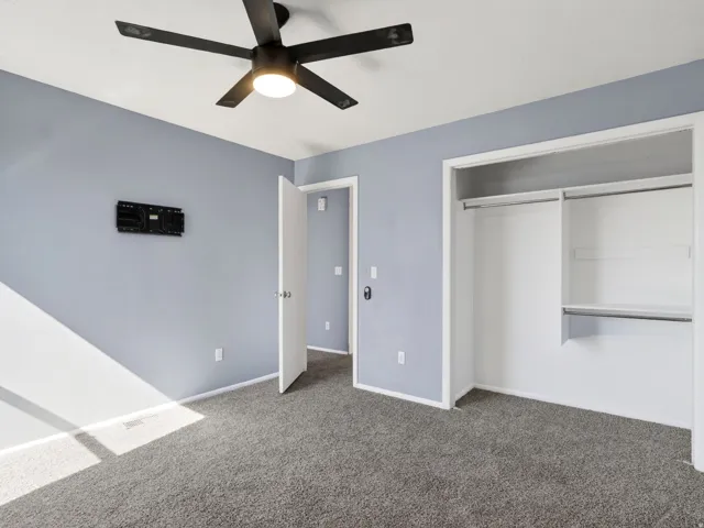 Bedroom featuring gray carpeting, light blue walls, and a black ceiling fan with integrated lighting