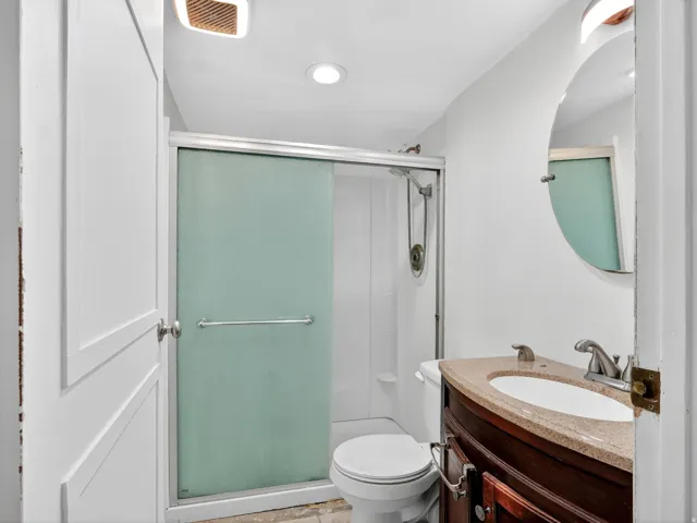 Bathroom featuring a shower with frosted sliding glass doors, a vanity with a dark wood-finish cabinet, and a countertop with an integrated sink