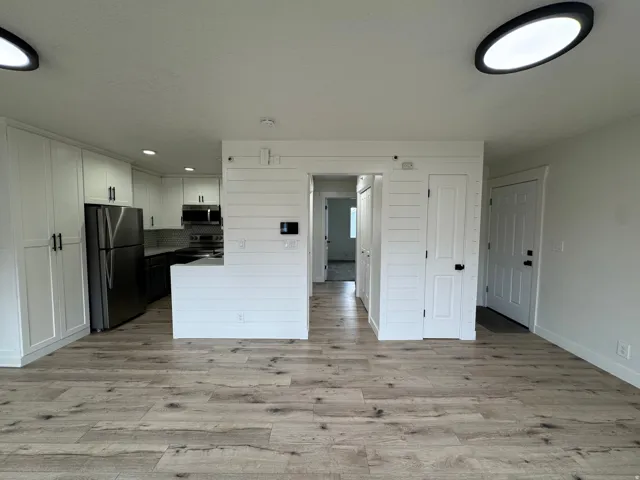 Open-concept living area with wood-finish flooring, white walls, and contemporary ceiling lighting