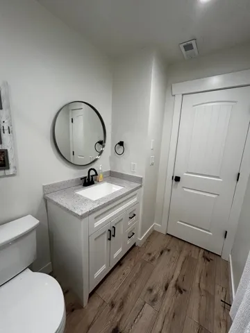 Modern bathroom featuring a white vanity with shaker-style cabinetry, a speckled countertop, and a white undermount sink
