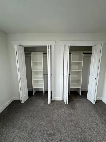 Room featuring two closets with white bi-fold doors, each equipped with built-in shelving units and hanging rods